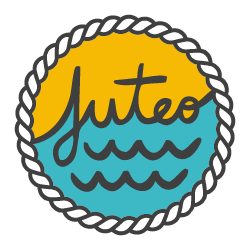 Das Logo ist kreisförmig mit einer weißen Kordel am Rand. Innendrin steht juteo. Darüber ist der Hintergrund gelb, darunter blau mit Wellen.